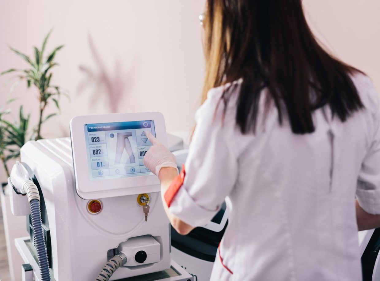 A practitioner setting the energy and pulse width on a diode laser console before a session
